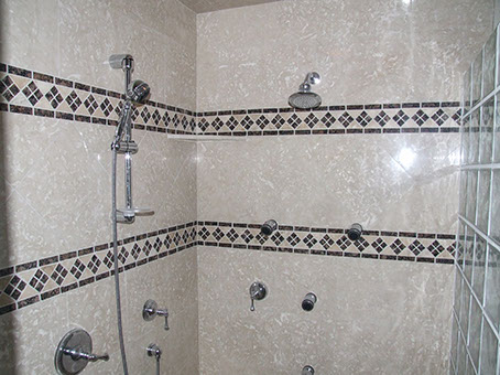 Stone tile and intricate contrasting tile shower surround by Rock Solid Creations, Inc.
