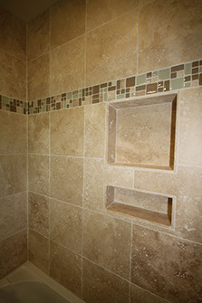Shower stall stone tiling with inset glass mini tiles.