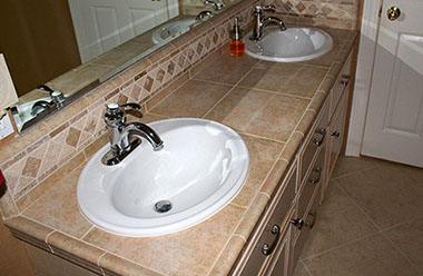 Stone tile on backsplash and surface of bathroom vanity by Rock Solid Creations, Inc.