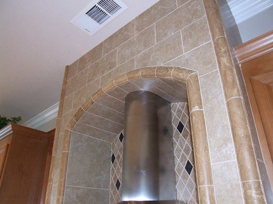 Stone tile installation in kitchen above stove.