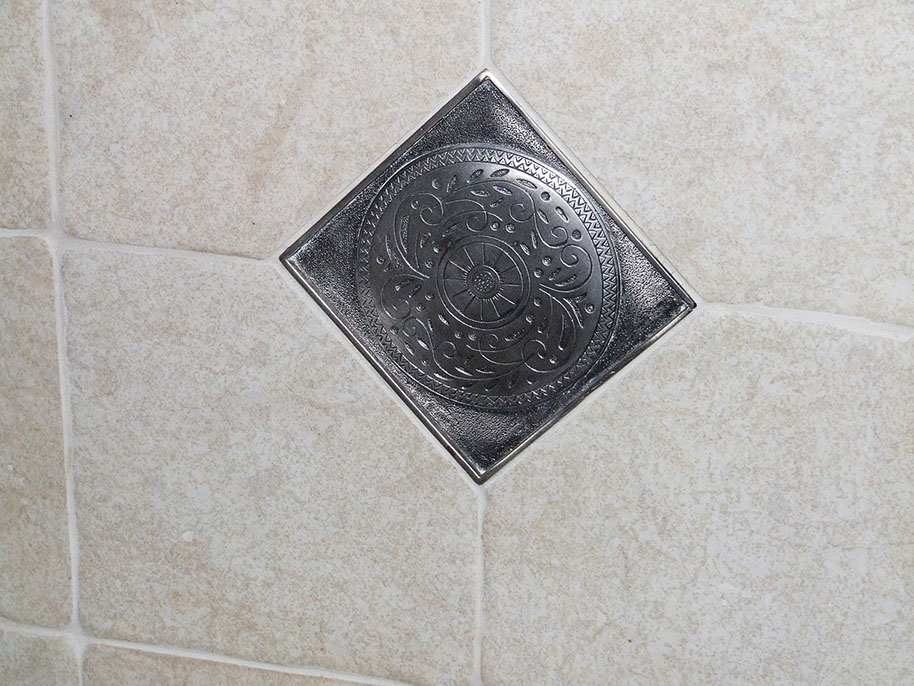 Metal inset detailing in bathroom stone tile wall.