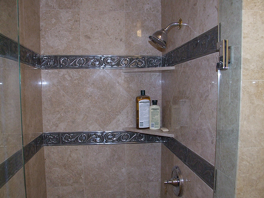 Stone tile shower stall showing metal inset details, installation and design by Rock Solid Creations.