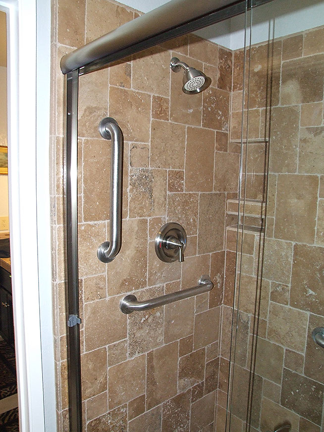Tan stone shower stall with complex stone tile patterning.