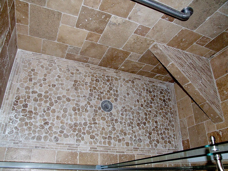 Stone tile walls and sliced river rock flooring for shower stall.